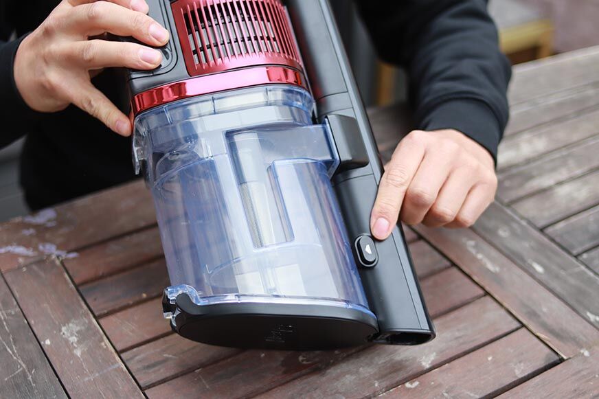 Man sieht den Knopf zum Öffnen des Schmutzbehälters